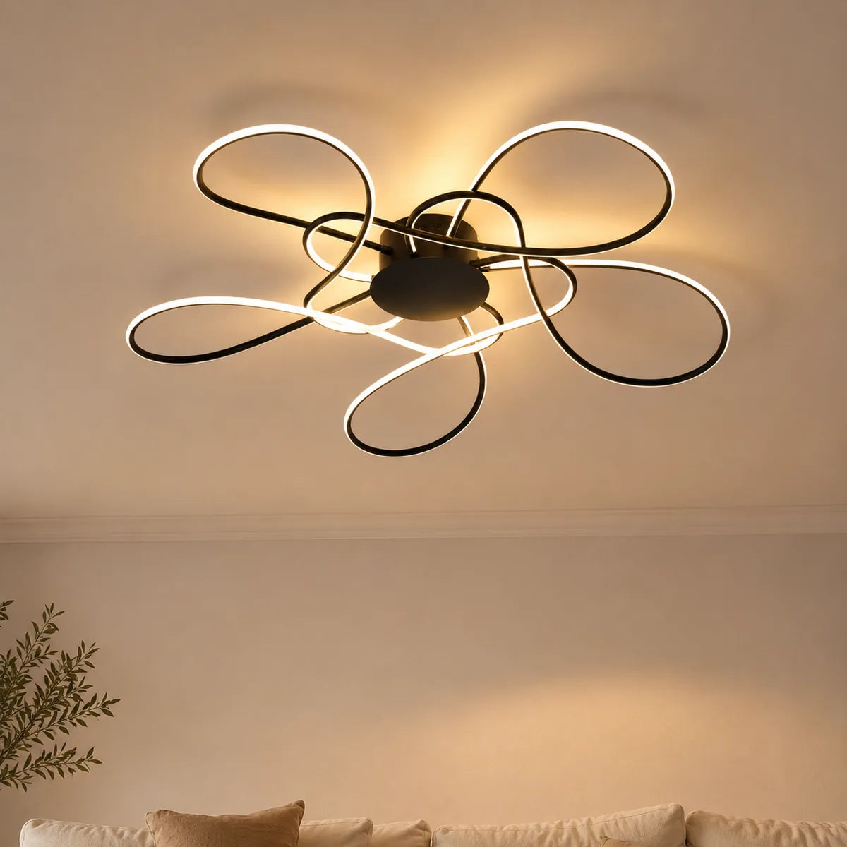 Plafonnier LED design noir en corolle allumé dans un salon chaleureux en lin et chêne clair
